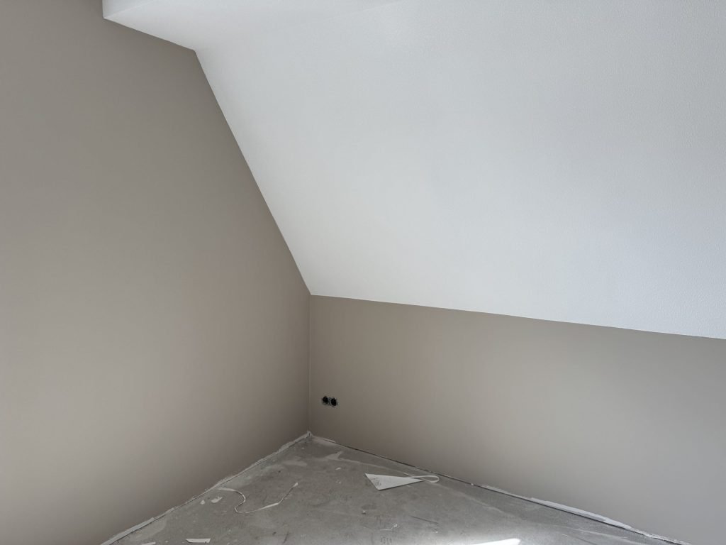 Zolderkamer met een schuine wand en egaal gesausde muren in een nieuw huis